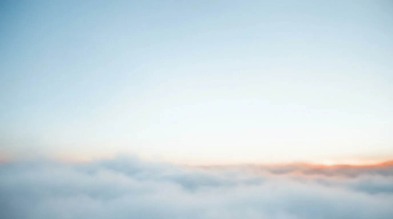 A summit clearing above the clouds at deep dusk — a soft cloud deck under a darkened sky with a warm ember sunrise raking the horizon