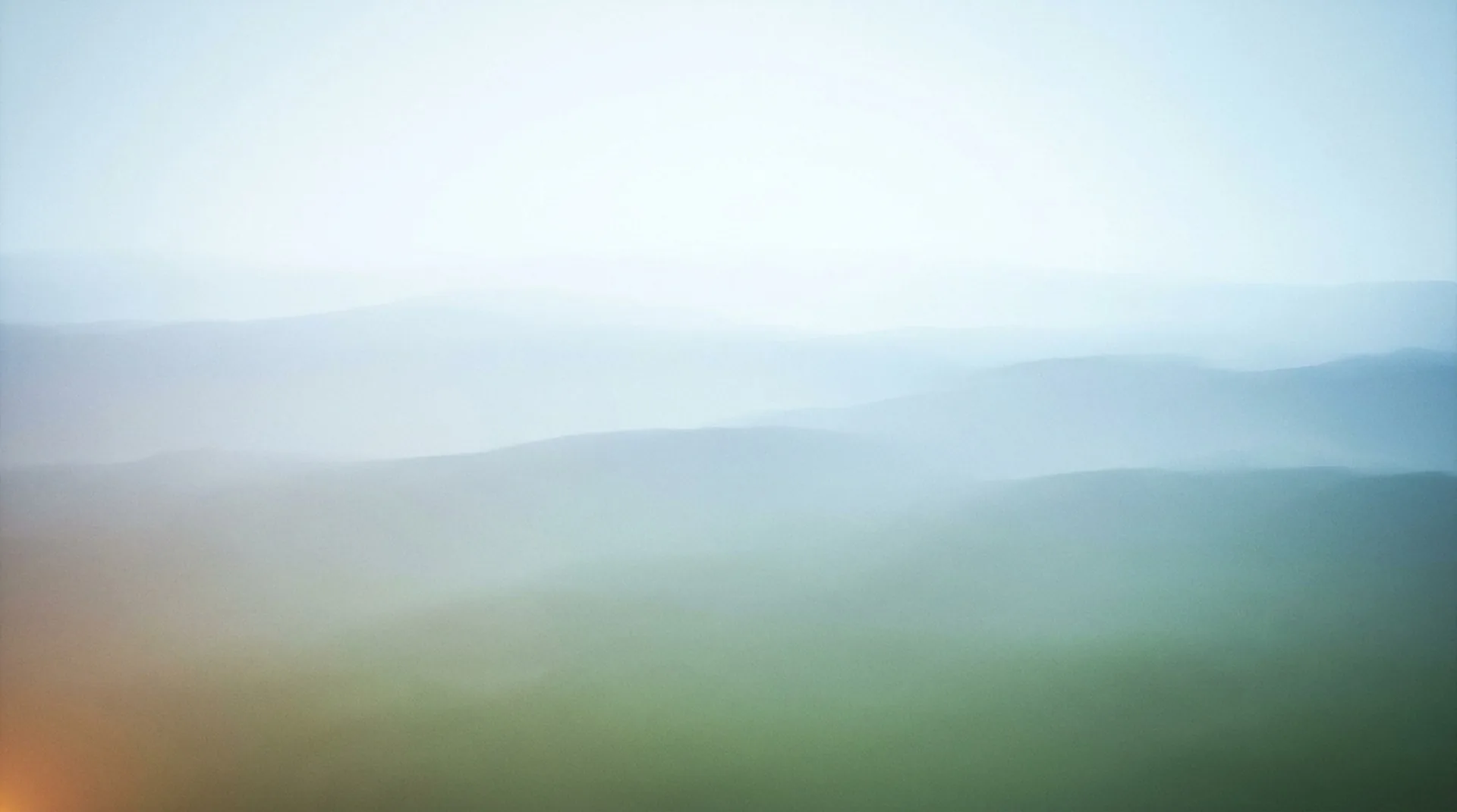 A cool layered-ridge vista receding into haze — the summit view after the climb