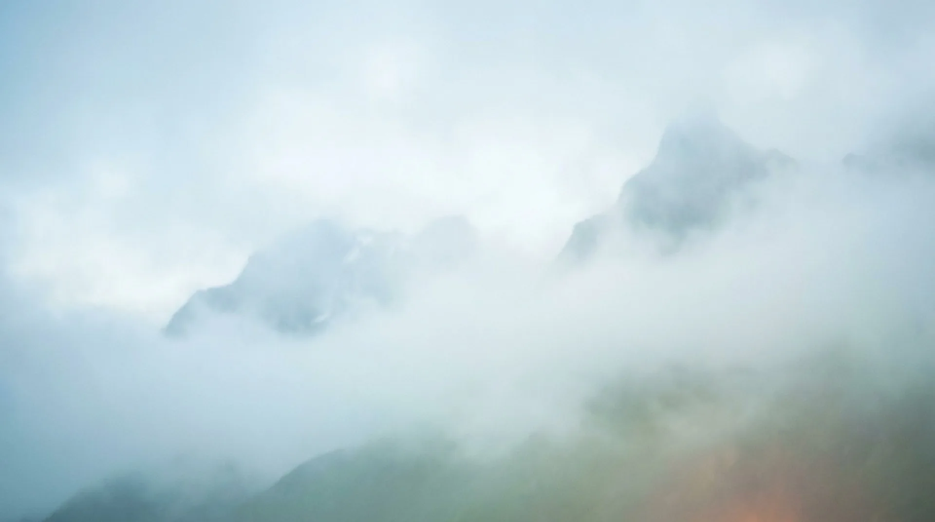 An ethereal open valley of peaks dissolving into luminous cloud — emerging from the fog into the clearing